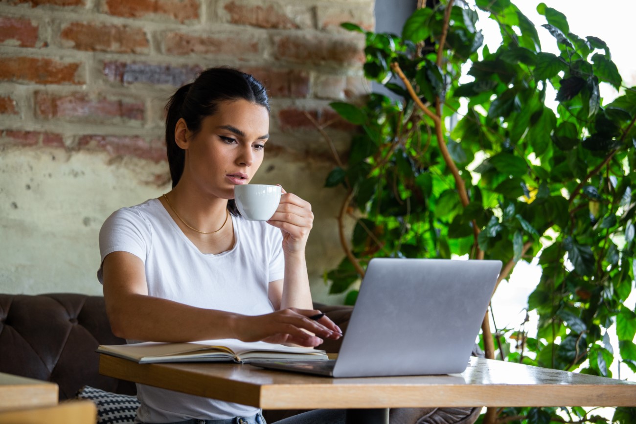 Young businesswoman is working in a cafeteria in her break.Woman taking a break. Enjoying work from coffee shop. Doing Business From coffee shop