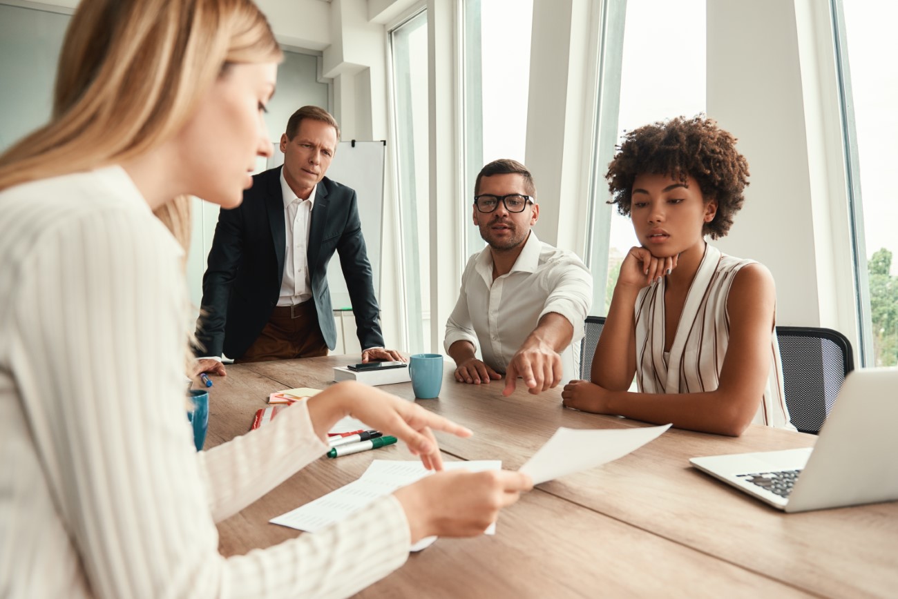 Business meeting. Group of young business people looking at documents and discussing something while sitting at the office table