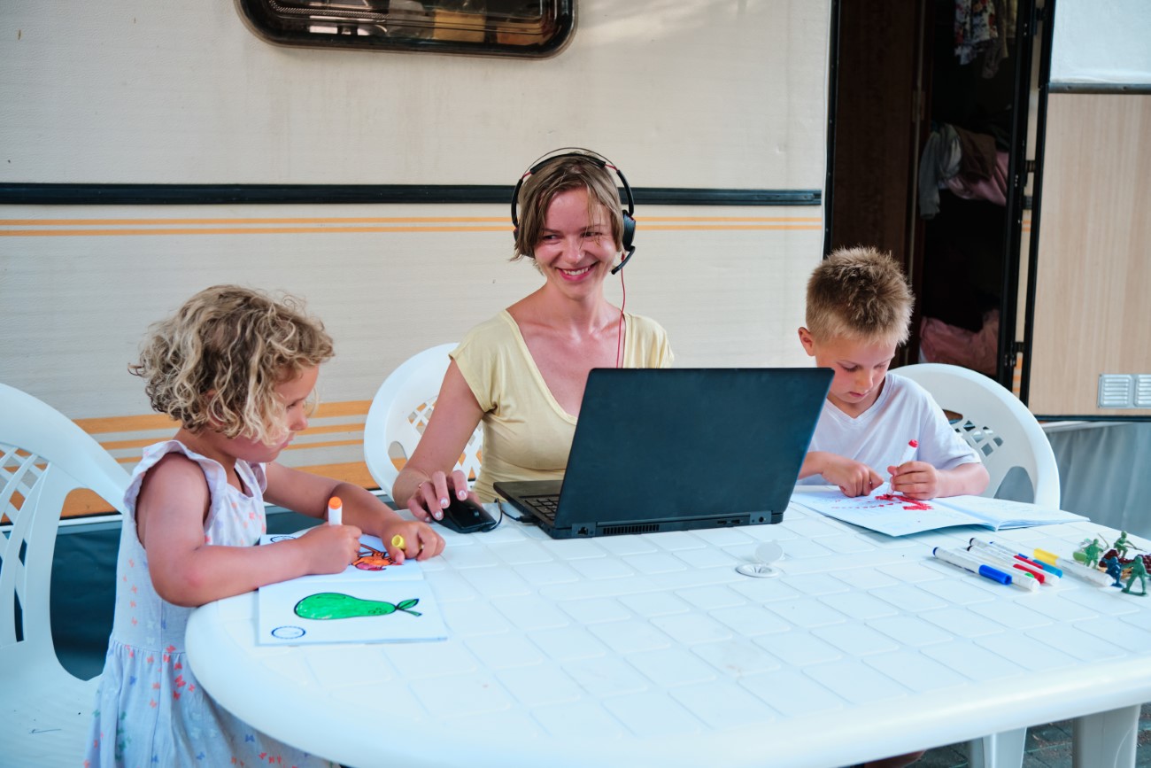 family at a camping with mother working and kids drawing