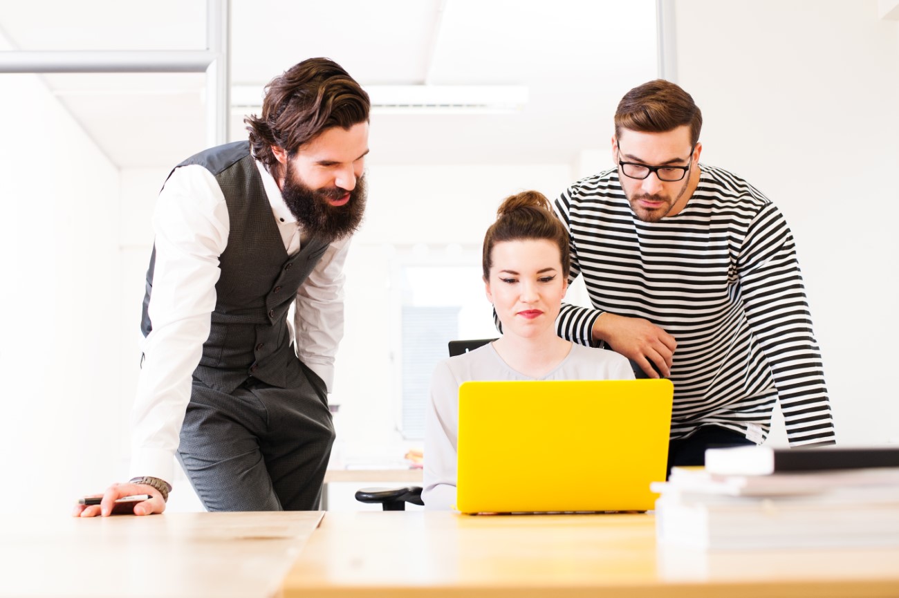 Colleagues using laptop at desk