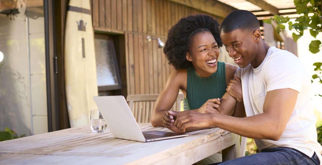 Couple With Laptop Outdoors Sitting At Table At Home